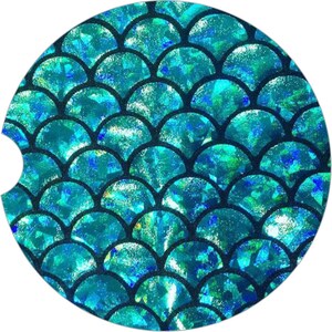 May include: A round, blue and black patterned coaster with a mermaid scale design. The scales are iridescent and shimmer in the light.