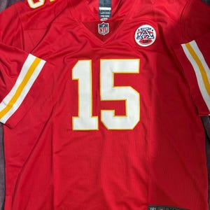 Puede incluir: Una camiseta de f&uacute;tbol roja talla XL con detalles blancos y amarillos. El n&uacute;mero 15 se muestra en blanco en la parte delantera, con el n&uacute;mero 5 en el hombro izquierdo. El logotipo de la NFL es visible en el cuello.
