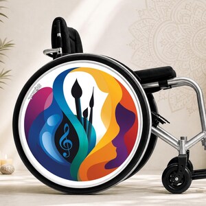 Peut inclure: Un fauteuil roulant doté d'un enjoliveur circulaire avec un motif graphique abstrait et vibrant. L'illustration présente des formes fluides en bleu, jaune, orange et violet, intégrant des silhouettes de pinceaux et une clé de sol musicale.