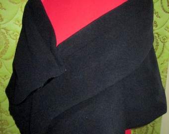 May include: A black sweater draped over a red turtleneck shirt. The sweater is folded in half and the sleeves are crossed over each other.