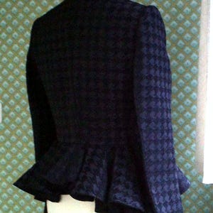 May include: A black and blue patterned jacket with a ruffled hem. The jacket has a high collar and a fitted silhouette.