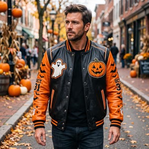 May include: A black and orange varsity jacket featuring a white ghost patch on the right chest and a jack-o'-lantern patch on the left chest. The sleeves are orange with black bat patterns, the text OCT 31, and striped black and orange ribbed cuffs.