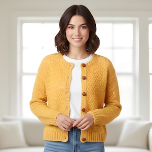May include: A woman wearing a yellow cardigan sweater with a textured knit design and brown buttons. The sweater is paired with a white shirt and blue jeans. The background includes a window and a white couch.