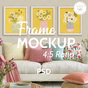 May include: Three framed floral art prints with yellow backgrounds and white frames are displayed above a white sofa. The prints feature colorful flowers in vases. Decorative pillows in various colors and patterns are arranged on the sofa.