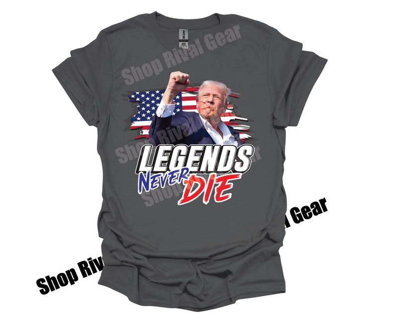 May include: A grey t-shirt featuring a graphic of a man in front of an American flag. The text "LEGENDS NEVER DIE" is printed in blue and red lettering.