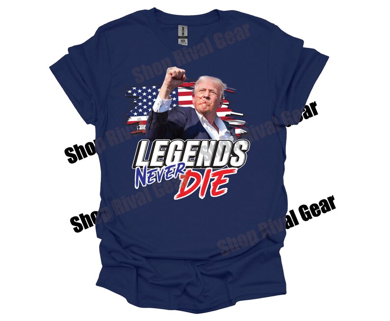May include: A navy blue t-shirt featuring a distressed American flag design and the text "Legends Never Die" in white and red lettering. The image depicts a man in a suit with his fist raised in the air.