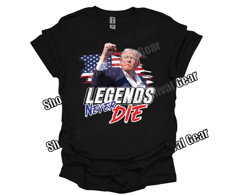 May include: Black t-shirt featuring a graphic of a man with his fist raised in the air. The graphic is in front of a red, white and blue American flag. The text "LEGENDS NEVER DIE" is printed in white, red and blue lettering below the graphic.