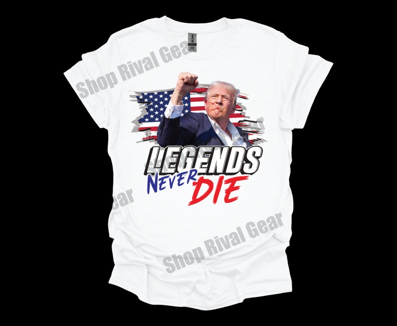 May include: White t-shirt featuring a graphic of a man in front of an American flag with the text "LEGENDS NEVER DIE" in bold, red, white and blue lettering.