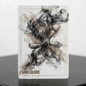 Puede incluir: Una carta de juego rectangular con una ilustración central de una figura compuesta por humo negro arremolinado y partículas de arena dispersas. El texto "TOKEN UNIT SHURIMA" y "SAND SOLDIER" está impreso en negro en la parte inferior.