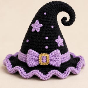 Puede incluir: Un sombrero de bruja tejido a ganchillo en color negro con la punta curvada, decorado con estrellas y puntos de color lila. La base tiene una banda lila con un lazo central y una hebilla cuadrada dorada, con un borde tejido en color lila.