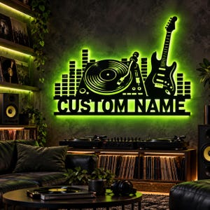 Könnte beinhalten: Ein schwarzes Wand-Schild mit der Silhouette eines Plattenspielers, einer Gitarre und eines Sound-Equalizers, beleuchtet durch eine hellgrüne LED-Hintergrundbeleuchtung. Das Schild enthält den Text CUSTOM NAME in fetten Großbuchstaben.