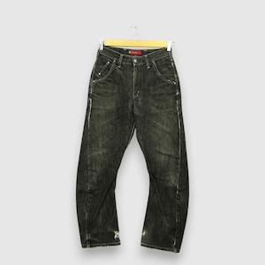 Può includere: Jeans in denim lavato scuro appesi a una gruccia di legno. I jeans hanno un aspetto sbiadito e usurato con accenti bianchi lungo le cuciture e usura sugli orli inferiori. I jeans hanno un classico design a cinque tasche.
