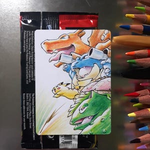 May include: A rectangular bristol card featuring a hand-drawn coloured pencil illustration of Charizard, Blastoise, Pikachu, and Venusaur, positioned over a sealed red and black Pokemon booster pack with visible text and a barcode.