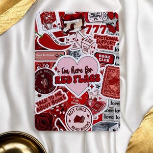 May include: A rectangular e-reader cover featuring a collage of red, white, and pink stickers. The central sticker is a pink heart with the text 'i'm here for RED FLAGS'. Other stickers include a chilli pepper, a rose, dice, and book-themed phrases.