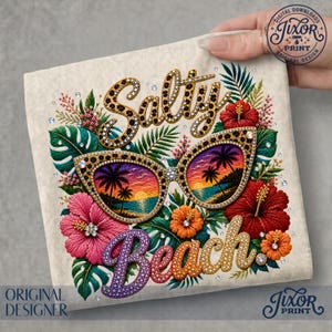 Peut inclure: Motif brodé avec les mots "Salty Beach" et des lunettes de soleil reflétant un coucher de soleil sur l'océan. Le motif comprend des fleurs et du feuillage tropicaux dans des tons de rose, d'orange et de vert, avec des accents de strass.