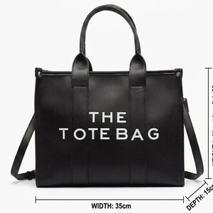 May include: Black tote bag with the text "THE TOTE BAG" in white. The bag has a width of 13.8 inches, a depth of 5.9 inches, and a height of 11 inches without the handle. It features a shoulder strap and two top handles.