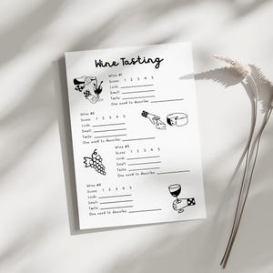 May include: A white paper titled "Wine Tasting" with black illustrations and fill-in-the-blank sections for wine evaluation. Includes sections for scoring, look, smell, taste, and a one-word description. Features wine-related graphics.