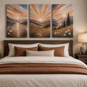 May include: A triptych canvas wall art set depicting a sunrise over a mountain landscape with a lake, pine trees, and white flowers. The scene features warm orange, yellow, and brown tones. The artwork is displayed above a bed with white and brown bedding.