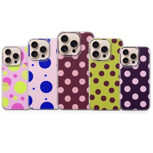 Può includere: Cinque cover per smartphone disposte in fila, ognuna caratterizzata da un distinto motivo a pois. I design includono rosa chiaro con cerchi neon, rosa pallido con cerchi blu, bordeaux scuro con cerchi rosa, verde lime con cerchi scuri e viola con cerchi rosa.