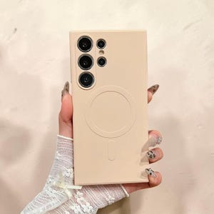 Może przedstawiać: Jasnobeżowe etui na telefon z okrągłym wzorem i pionowym paskiem na dole. Etui ma wiele wycięć na aparat u góry. Etui jest trzymane przez dłoń w białej koronkowej rękawiczce.