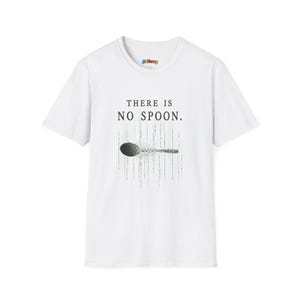May include: White t-shirt featuring the phrase "THERE IS NO SPOON." above a grey and black graphic of a spoon. The spoon design has a pixelated effect. The shirt has a crew neck and short sleeves.