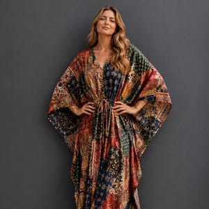 Könnte beinhalten: Ein bodenlanges Kaftan-Kleid mit einem mehrfarbigen Patchwork-Muster in den Farben Dunkelrot, Marineblau, Waldgrün und Gold. Das Kleidungsstück hat weite, fließende Ärmel, einen V-Ausschnitt und ein Taillenband mit Kordelzug zur Anpassung.