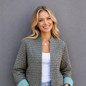 Puede incluir: Una chaqueta de manga larga abierta por delante con una base de color verde azulado y un patrón repetitivo de pequeñas flores rojas con centros amarillos. La chaqueta tiene un cuello tipo mandarín y puños que muestran un forro de rayas verticales.