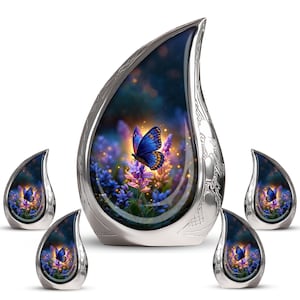 May include: A silver teardrop-shaped urn with a butterfly design. The urn has a detailed floral and butterfly scene inside, with a blue butterfly. Four smaller matching urns are also present.