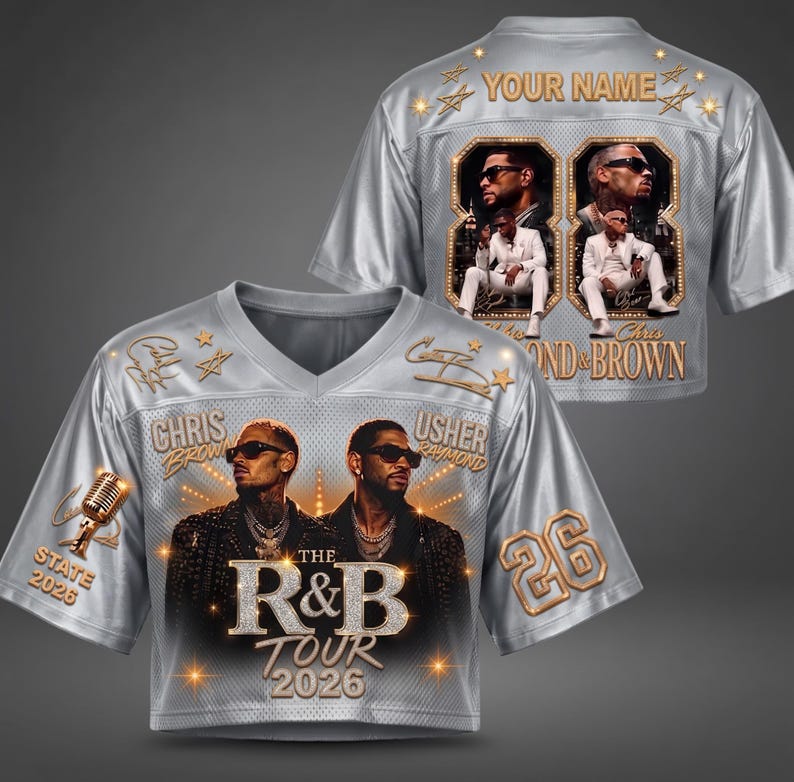 May include: A silver V-neck jersey featuring a graphic print of Chris Brown and Usher. The front displays the text The R&B Tour 2026, a microphone, and the number 26. The back includes the text Your Name, two framed photos, and Chris & Brown.
