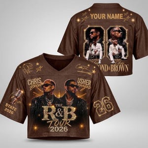 May include: A brown V-neck jersey featuring a graphic of Chris Brown and Usher, the text "The R&B Tour 2026," and the number 26. The back displays "Your Name" with two framed photos of the artists in white suits and the text "Chris & Brown."