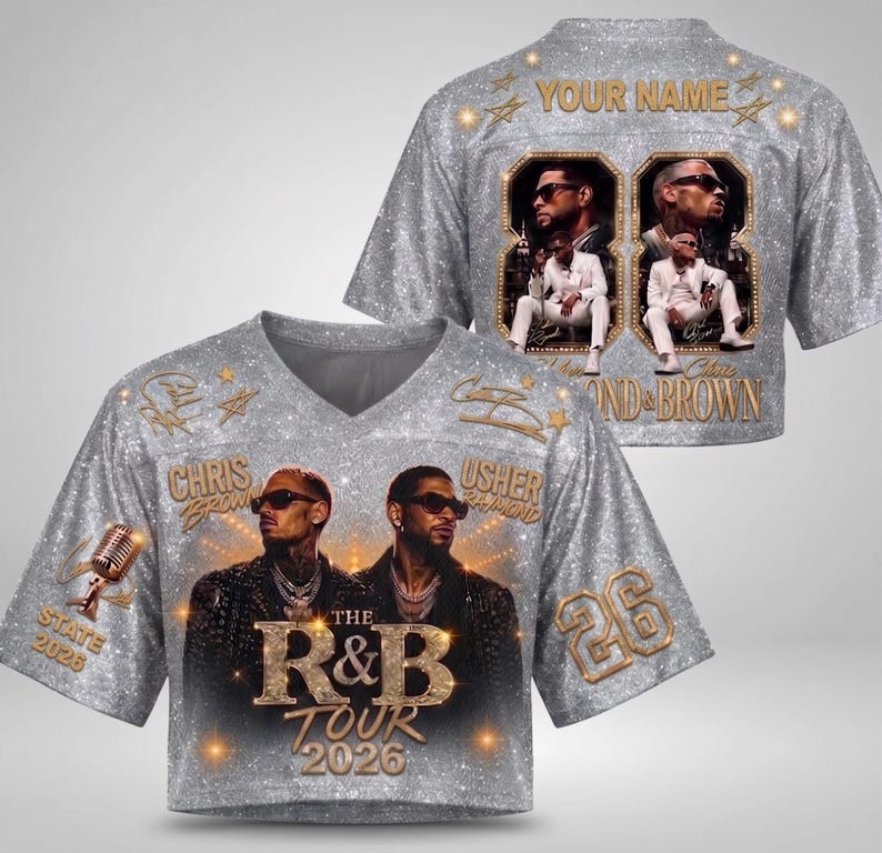 May include: A silver glitter-textured V-neck jersey featuring photographic prints of Chris Brown and Usher, the text "THE R&B TOUR 2026", "STATE 2026", "26", and "YOUR NAME". The design includes gold-toned accents, a microphone graphic, and star motifs.