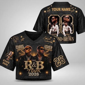 May include: A black short-sleeved jersey featuring gold graphics of Chris Brown and Usher, the text "THE R&B TOUR 2026", "STATE 2026", and the number "26". The back displays "YOUR NAME" with two framed photos of performers in white suits.