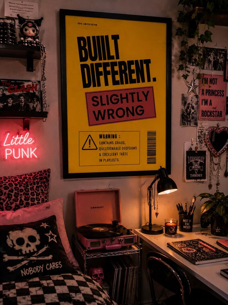Bold yellow funny typography wall art in a black frame displayed in a punk-inspired teenage bedroom with vinyl records, neon sign, desk, plants, and alternative decor.