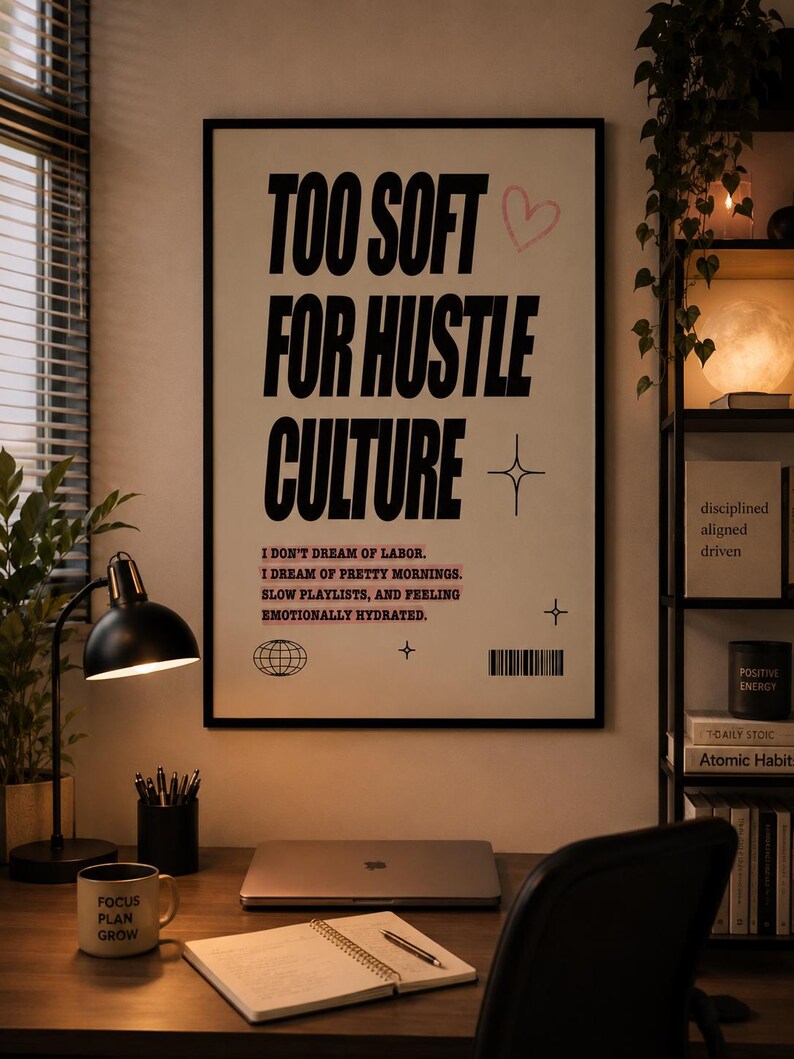 Motivational typography printable wall art in a black frame above a modern work from home desk with laptop, journal, plants, lamp, and cozy minimalist office decor.