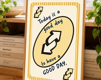 Puede incluir: Una impresión rectangular enmarcada con fondo color crema y bordes a rayas amarillas. El centro muestra un gran óvalo amarillo que contiene dos flechas negras que apuntan en direcciones opuestas y el texto Today is a good day to have a GOOD DAY.