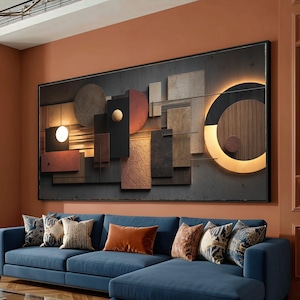 May include: Abstract wall art featuring geometric shapes in various textures and colors, including wood, metal, and stone. The artwork is framed in black and has a built-in light feature. The artwork hangs above a blue sectional sofa with decorative pillows.