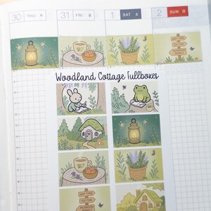 May include: A sheet of planner stickers with a woodland cottage theme. The stickers feature illustrations of a bunny, frog, teacups, lanterns, houses, and signs. The text "Woodland Cottage Fullboxes" is displayed on the sheet.