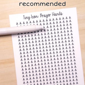 May include: A white sheet of paper with a pattern of tiny prayer hands, a white pen, and the text "Tweezers recommended" and "Tiny Icon: Prayer Hands". The image is on a light wood surface.