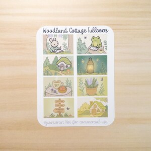 May include: A sticker sheet with the text "Woodland Cottage fullboxes" featuring illustrations of a rabbit, frog, cottage, lantern, tea, lavender, and a signpost. The illustrations are in a soft, pastel color palette.