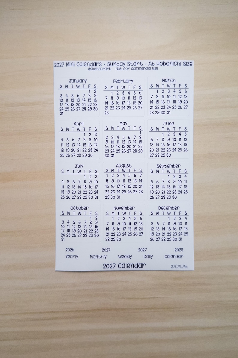 Pu&ograve; includere: Un foglio di carta bianco con un mini calendario 2027 che inizia di domenica, progettato per il formato A6 Hobonichi. Il layout include dodici griglie mensili da gennaio a dicembre, con etichette di testo aggiuntive per le viste annuali e mensili.