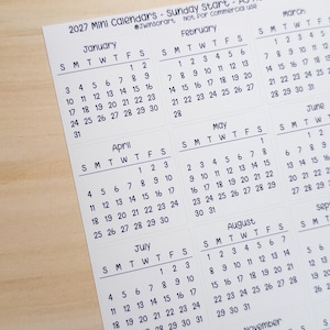 Pu&ograve; includere: Un foglio di carta bianco con mini calendari 2027 che iniziano di domenica, etichettati come A5 Hobonichi Size. La griglia mostra i mesi da gennaio a novembre con testo nero su sfondo bianco, incluso il testo 2027 Mini Calendars.