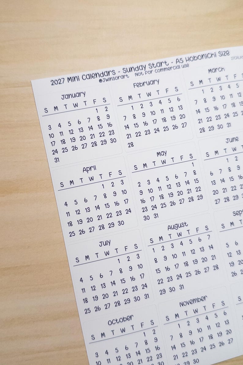 Pu&ograve; includere: Un foglio di carta bianco con mini calendari 2027 che iniziano di domenica, etichettati come A5 Hobonichi Size. La griglia mostra i mesi da gennaio a novembre con testo nero su sfondo bianco, incluso il testo 2027 Mini Calendars.