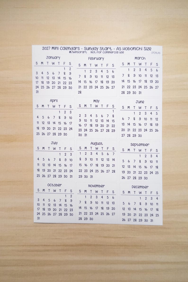 Pu&ograve; includere: Un foglio di carta bianco che presenta un mini calendario 2027 con inizio domenica, etichettato come A5 Hobonichi Size. La griglia mostra tutti i dodici mesi da gennaio a dicembre, ciascuno con le relative date e giorni della settimana in nero.