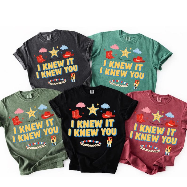 May include: Five short-sleeve crew neck t-shirts in charcoal, green, black, and maroon. Each shirt features a graphic print with the text "I KNEW IT I KNEW YOU" in yellow, accompanied by illustrations of cowboy boots, a star, clouds, and a bracelet.