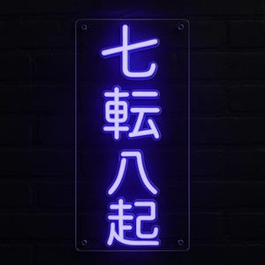 May include: A rectangular neon sign with the Japanese characters "七転八起" in bright blue against a dark brick wall. The sign has four mounting holes and a clear border.