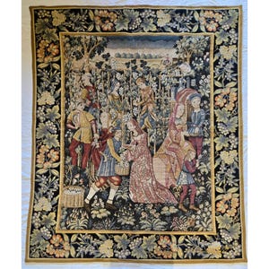May include: A large tapestry with a detailed scene of people in medieval clothing harvesting grapes. The central image is framed by a border of grape vines and floral patterns in shades of black, gold, and green. The tapestry depicts a vineyard scene.