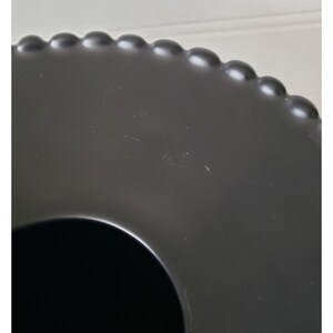 May include: Black ceramic serving tray with a beaded edge and a circular cutout in the center.