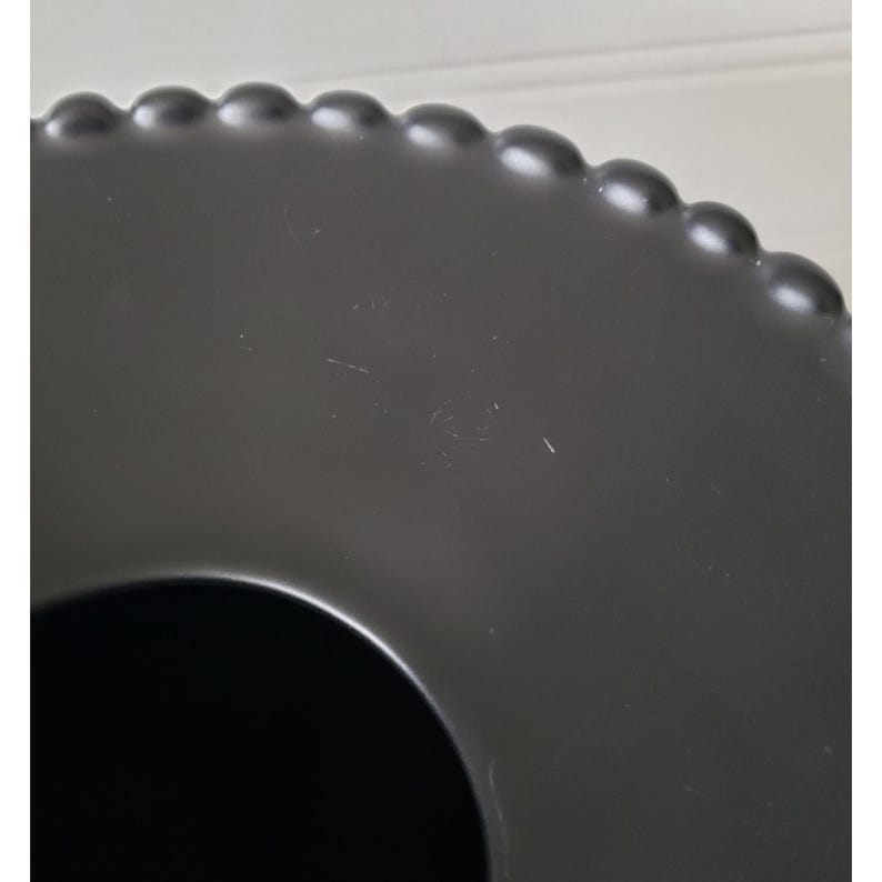 May include: Black ceramic serving tray with a beaded edge and a circular cutout in the center.
