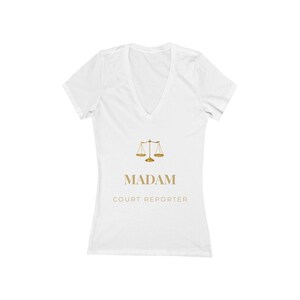 Peut inclure: T-shirt blanc à col en V avec un motif de balance de la justice doré. Le texte "MADAM COURT REPORTER" est imprimé en dessous en doré. Le t-shirt est fait d'une matière douce.