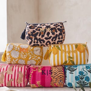 May include: Six rectangular quilted pouches with zip closures and tassels. The pouches feature various patterns including leopard print, yellow floral, yellow stripes with lemons, pink stripes with cheetahs, pink tiger print, and blue floral designs.